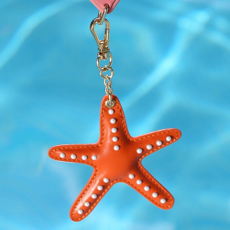 Keychain | Starfish | Orange hanging by a pool with a vibrant blue background, perfect accessory for personalization.