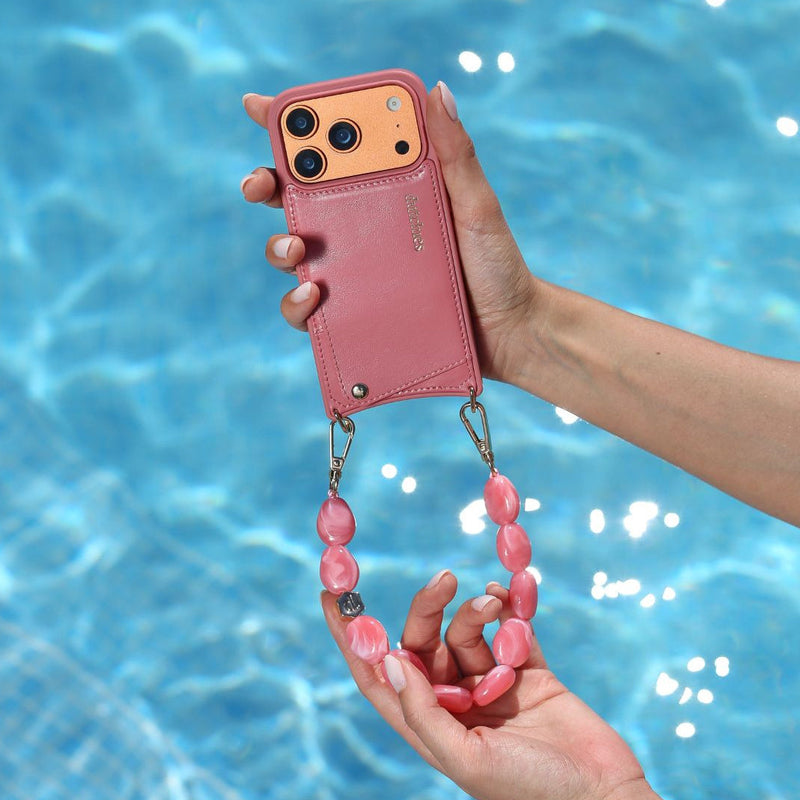 Phone Charm | Beaded | Ida stylishly held over a pool, showcasing its vibrant pink color and unique charm strap.