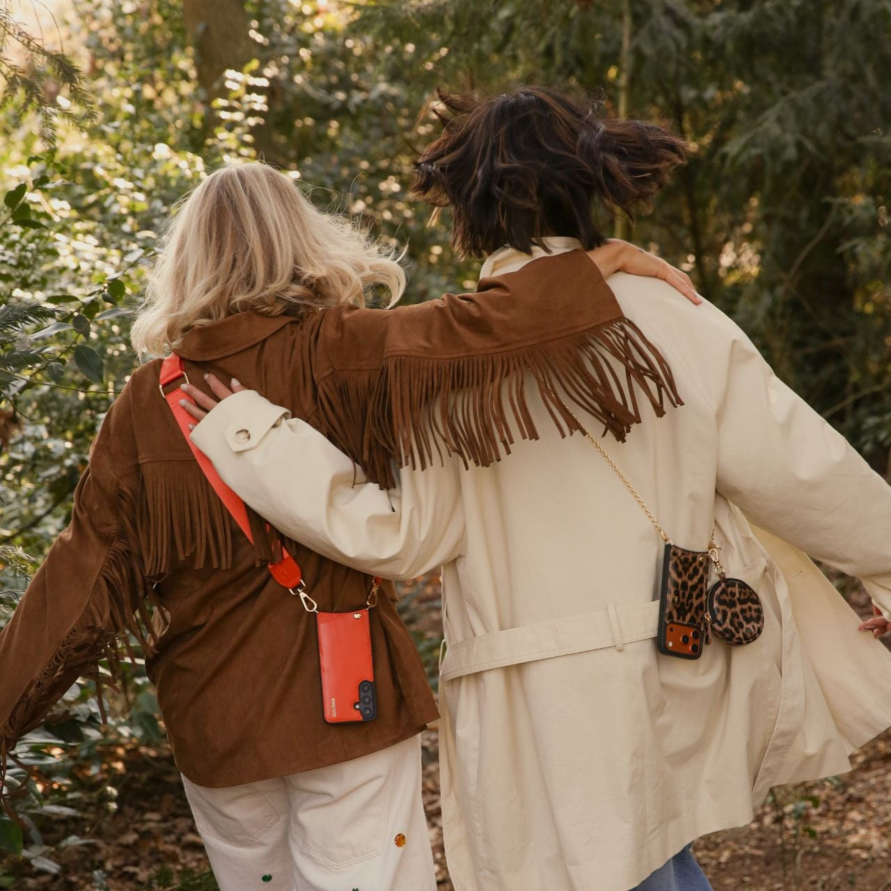 Two friends wearing stylish fringed jackets, showcasing the Spanish Chain Set | iPhone | Leopard in a lush outdoor setting.