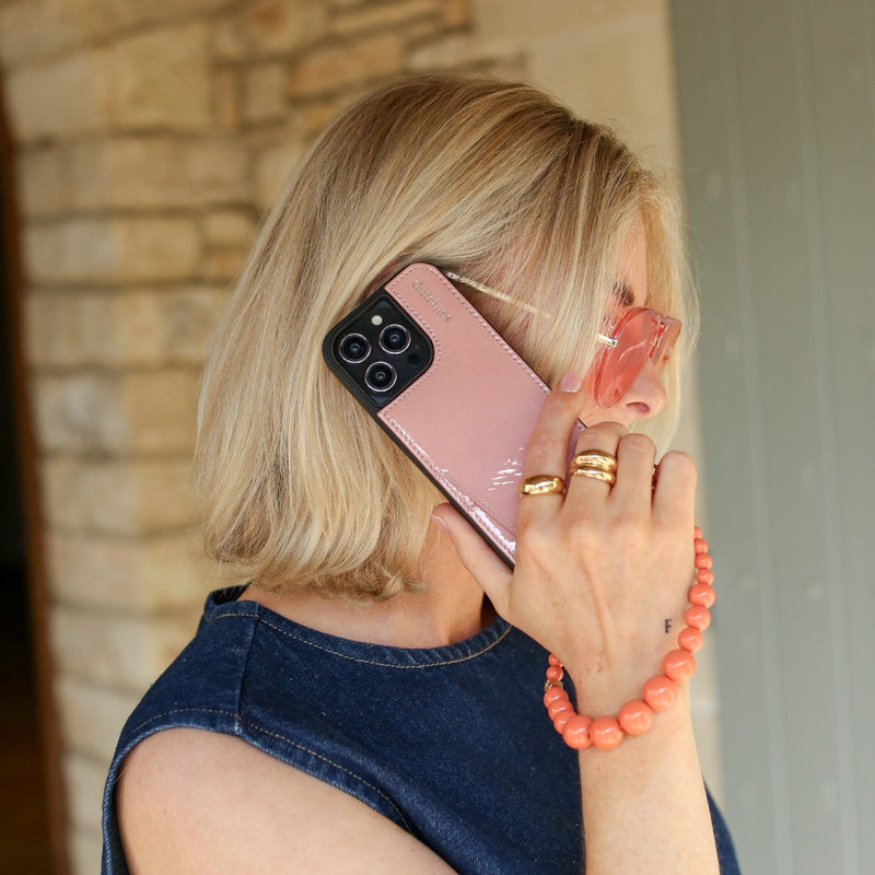 Woman holding a phone with an orange phone charm strap, showcasing the Phone Charm | Beaded | Freya.