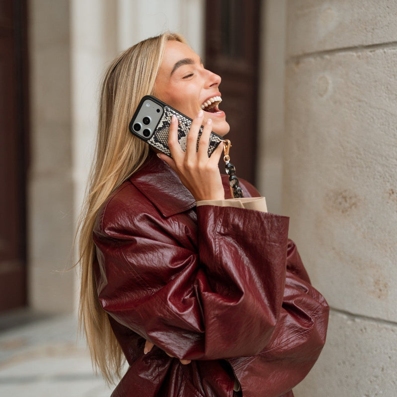 Woman smiling while using an iPhone Case | Snake with a cardholder, showcasing genuine leather and sporty style.