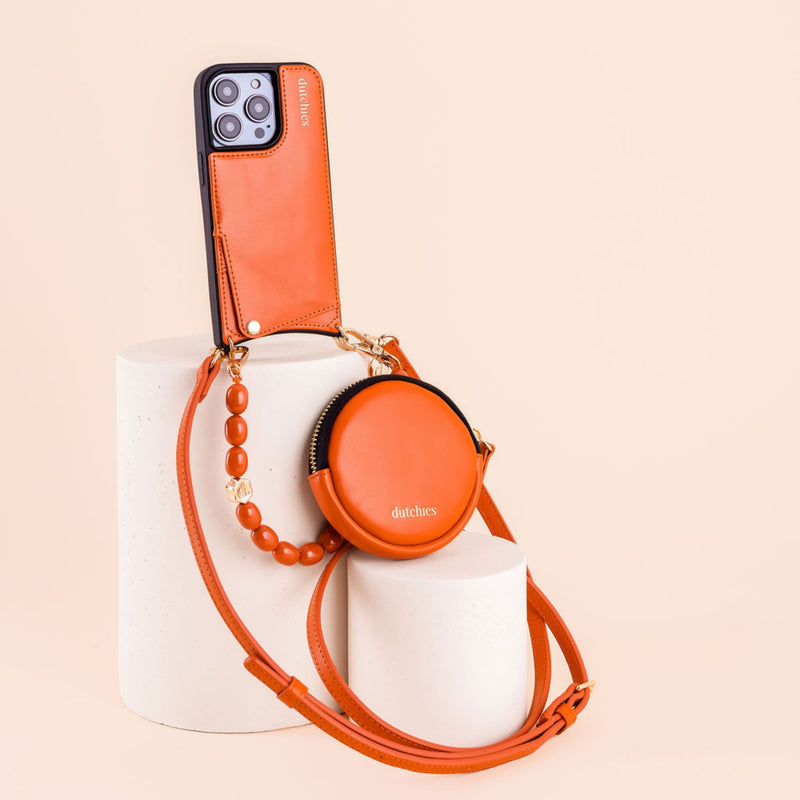 iPhone Case | Orange displayed elegantly with a stylish cardholder and matching accessory on a minimalist pedestal.