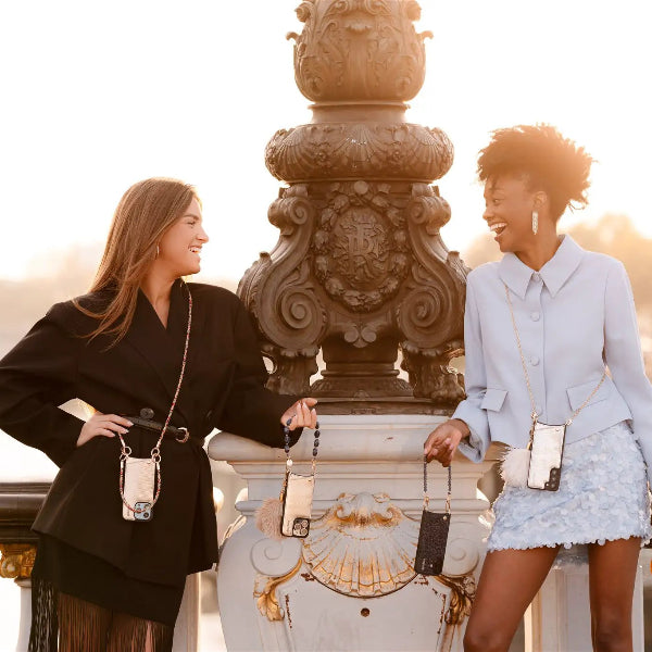 Women showcasing the Spanish chain set | iPhone | Silvy phone cases in a stylish outdoor setting.