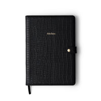 Stylish black leather notebook with crocodile texture and gold detailing for essential notes and planning.