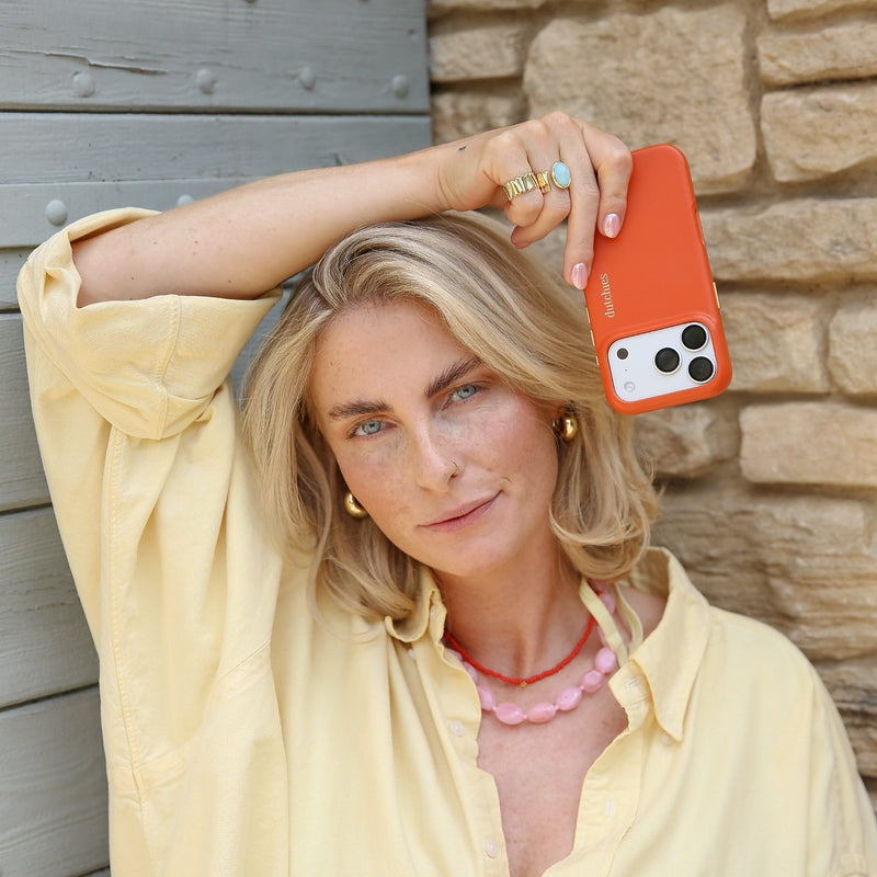 Woman holding an iPhone Case | Orange (Full Wrapped) while posing confidently in casual attire.