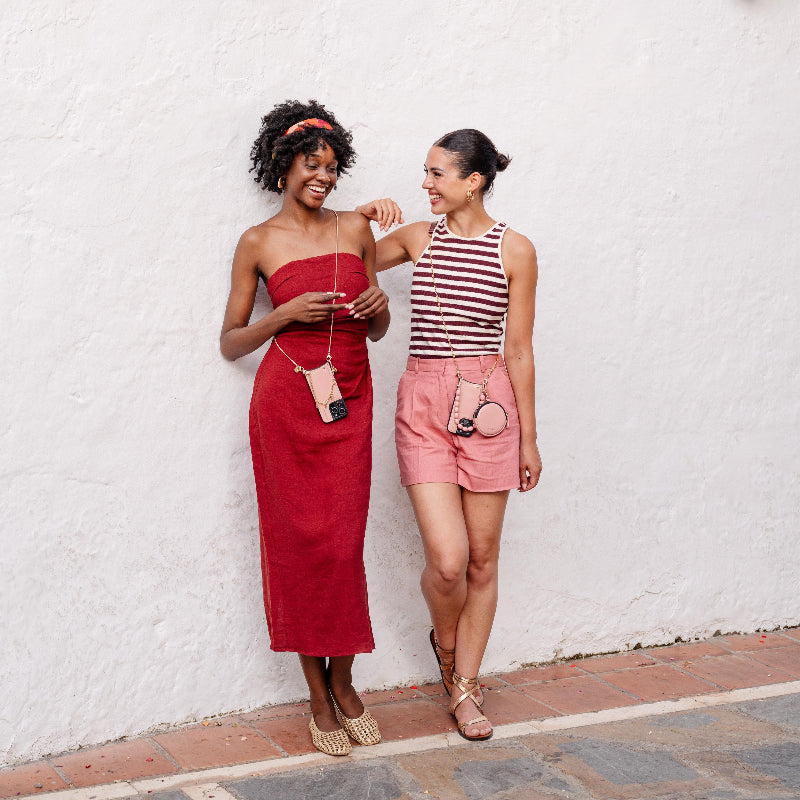 Two women standing in front of a wall with flower pots and wearing Dutchies phone cases