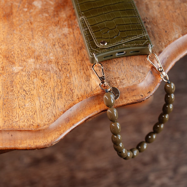 Phone Charm | Beaded | Arte on a wooden table, showcasing the green mobile phone charm with clips.