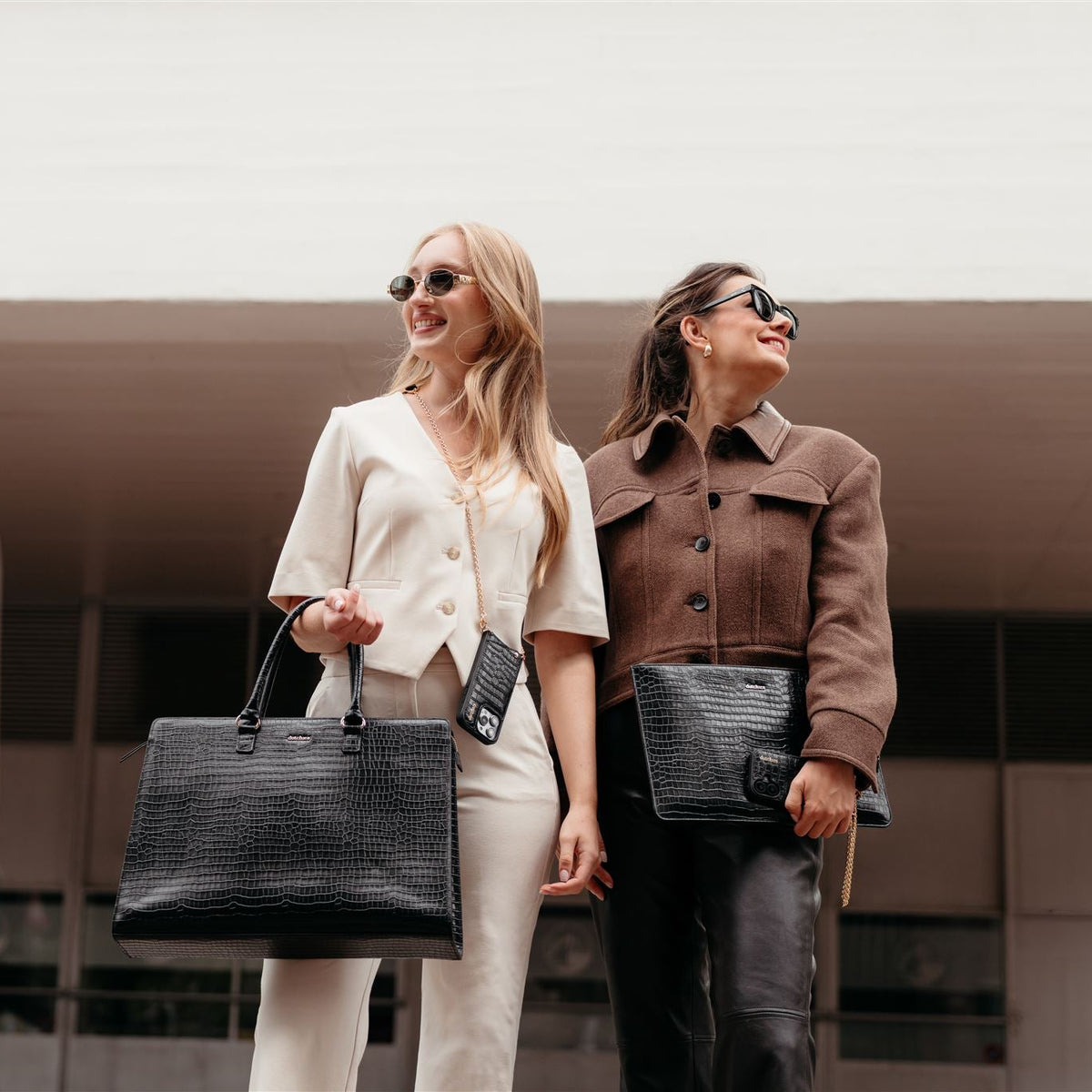 Zwei modische Frauen präsentieren die Laptop Bag Sharon | Noir und strahlen Stil und Eleganz aus.