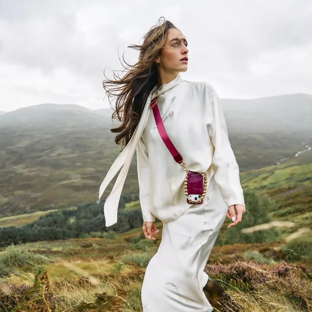 Woman wearing Phone Strap | Basic | Raspberry Red in a scenic landscape with mountains.