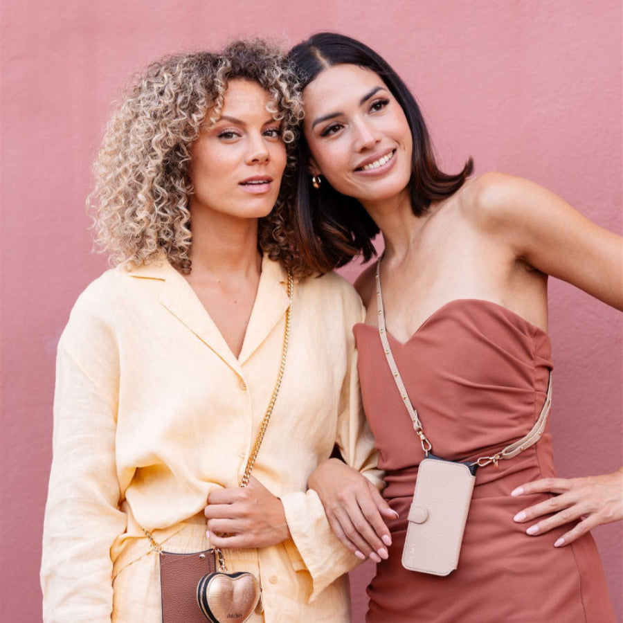 Dos mujeres mostrando la correa para teléfono | Slimline Studs | Beige con estilo y elegancia, vestidas con conjuntos chic.