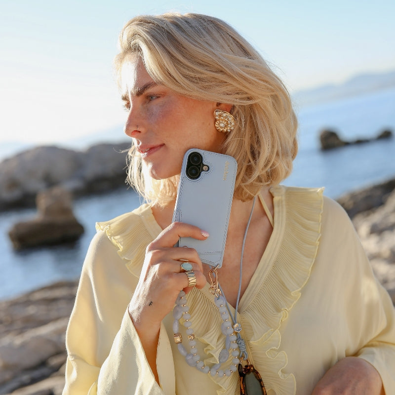 Handyanhänger | Perlen | Ann von einer stilvollen Frau am Meer präsentiert, die ihr elegantes Design und ihren Charme hervorhebt.