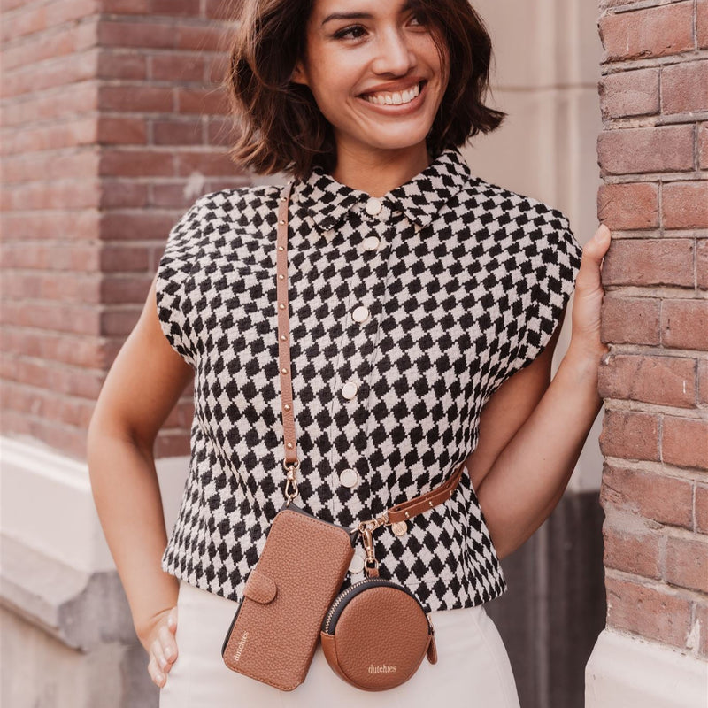 Woman smiling with Mini Phone Bag Emma | Brown hanging from her stylish outfit, showcasing elegance and functionality.