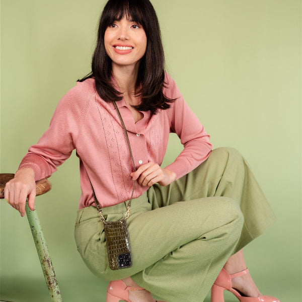 Model showcasing the Classic set | iPhone | Olive Green with stylish outfit against a pastel background.
