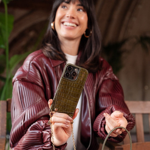 Femme tenant une Coque pour iPhone | vert olive avec porte-cartes, mettant en valeur style et fonctionnalité dans un cadre cosy.
