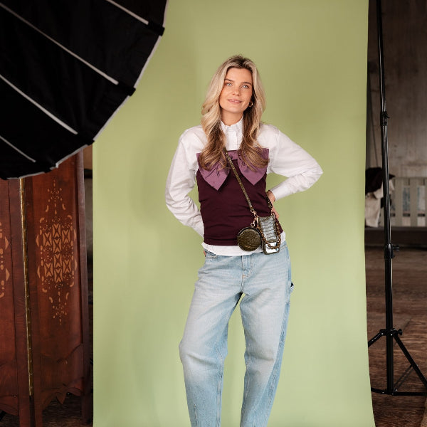 Luxury set | iPhone | Olive Green model posing against a green backdrop with stylish outfit and accessories.