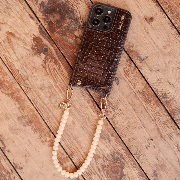 Phone Charm | Beaded | Marisa featuring a brown phone case with a pearl strap on wooden surface.