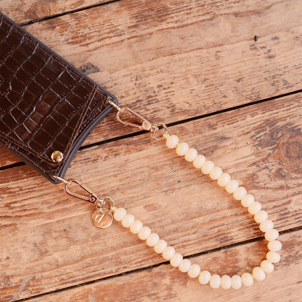 Phone Charm | Beaded | Marisa featuring elegant pearls attached to a stylish brown phone case.