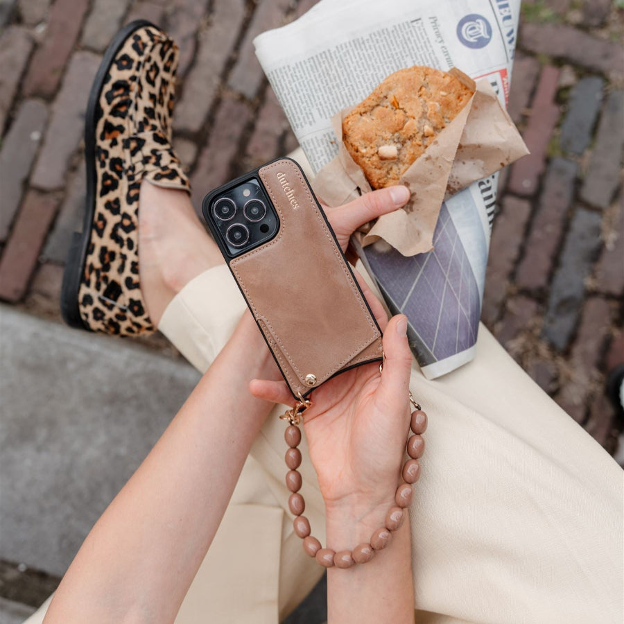Accesorio de teléfono | Con cuentas | Rachel, mostrado con una funda elegante para el teléfono, disfrutando de un snack mientras va de un lado a otro.