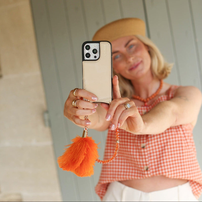 Phone Charm | Beaded | Vivianne displayed on a phone with a stylish woman holding it, showcasing vibrant orange colors.