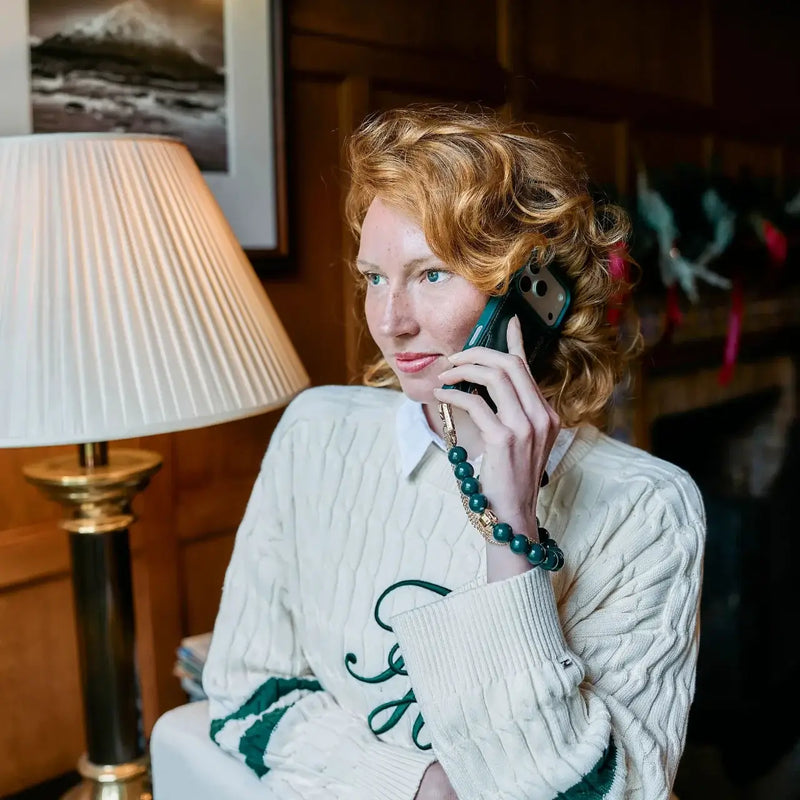 Woman with curly red hair holding a phone, showcasing the Charm Set | iPhone | Raspberry Red | Stella.
