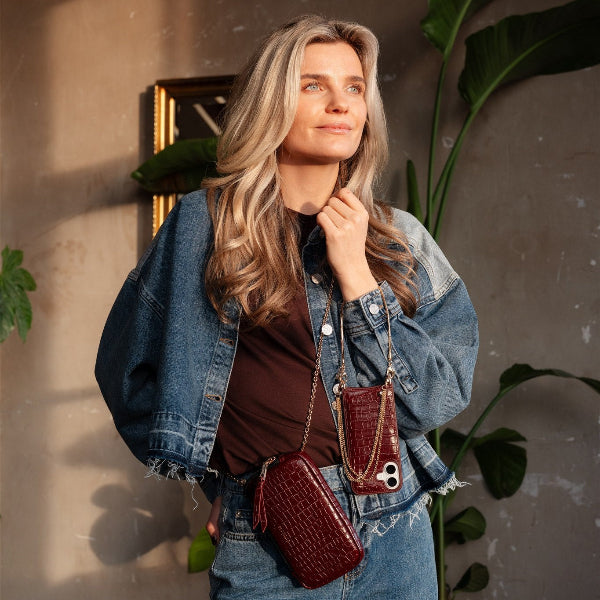 Woman wearing a Phone Bag Rose | Burgundy with a denim jacket and a stylish look.