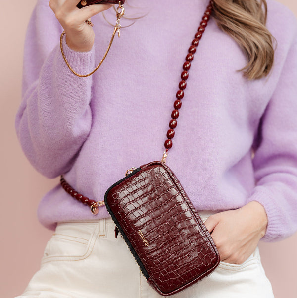 Phone Bag Rose | Burgundy displayed stylishly with a chic purple sweater and elegant strap.