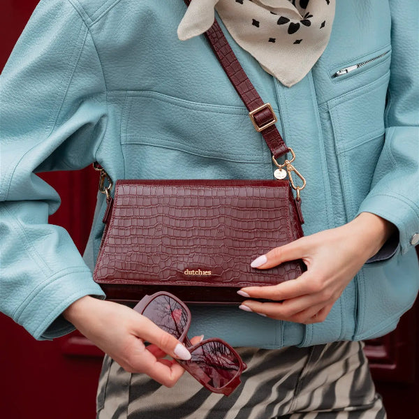 Sophie Crossbody Bag | Burgundy buren elegant med solglasögon, som visar dess exklusiva läderdesign.