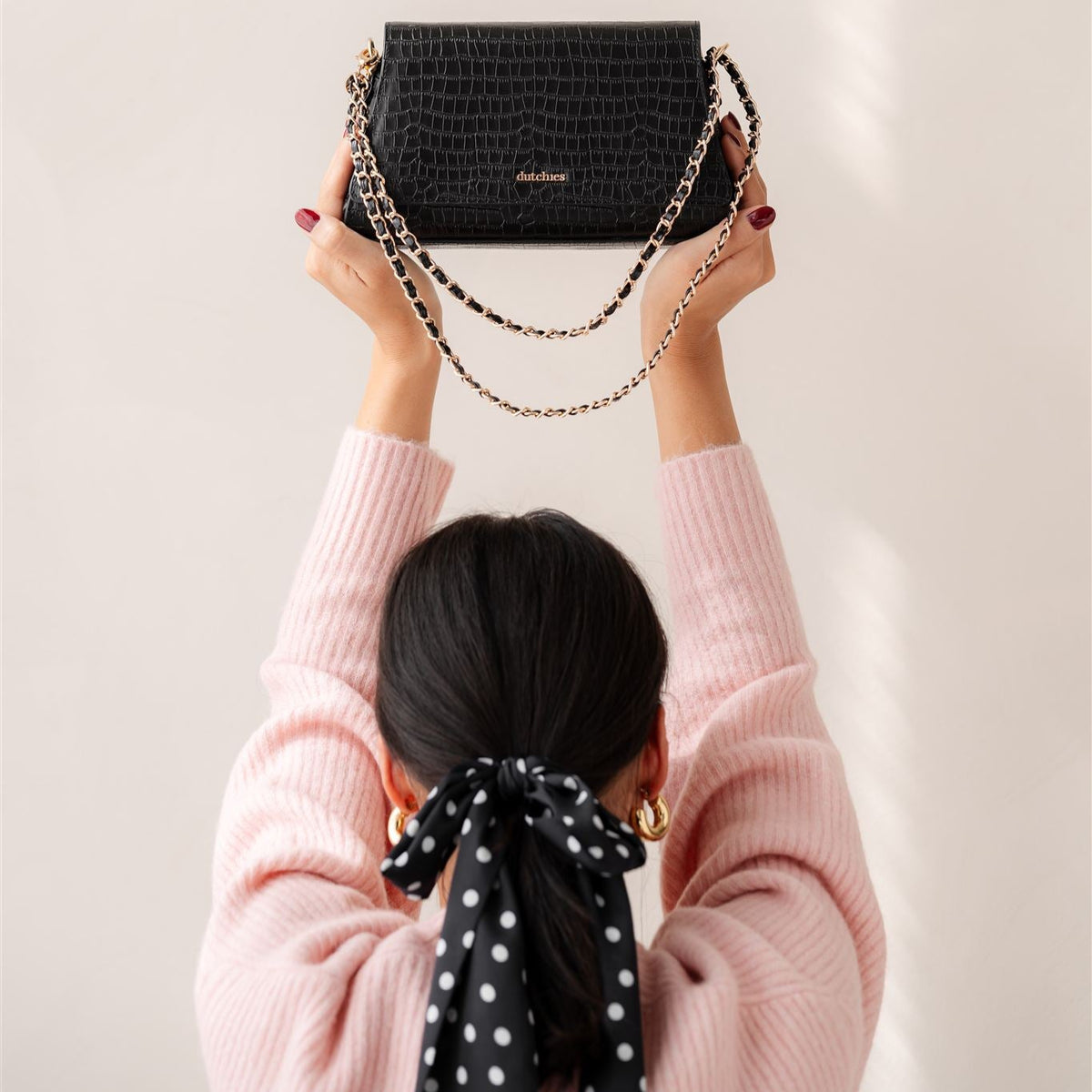 Sophie Crossbody Bag | Noir Gold holdt højt, der fremviser det elegante design som en stilfuld telefonpose.