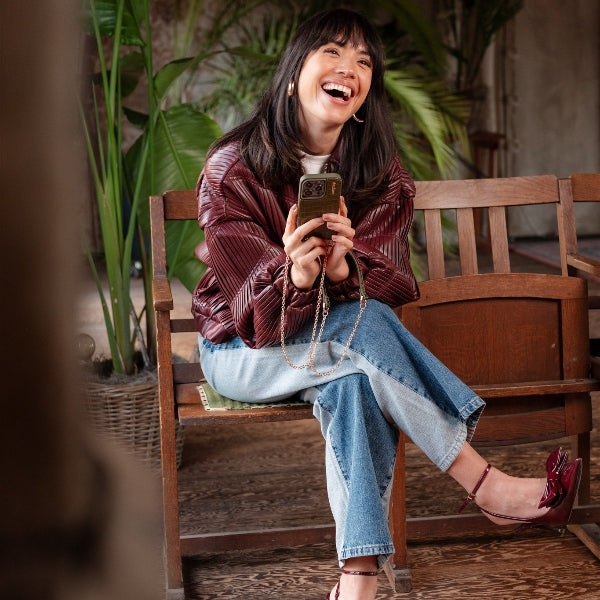 Spanish Chain Set | iPhone | Olive Green - Model laughing while holding the phone in a stylish setting.