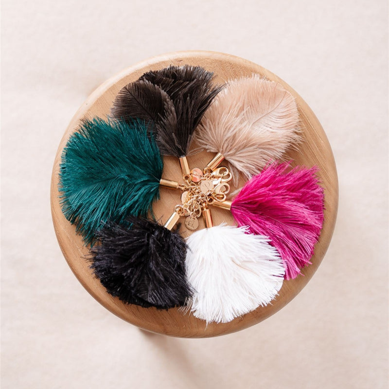 Colorful assortment of Vavavoom | Keychain fluffy charms on a wooden surface, showcasing unique ostrich feather designs.