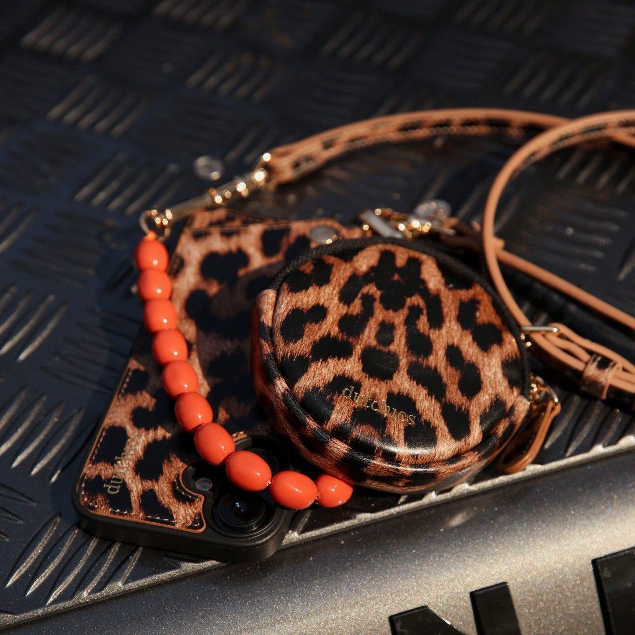 Mini Phone Bag Emma | Leopard displayed with accessories on a textured surface, showcasing its stylish design and versatility.