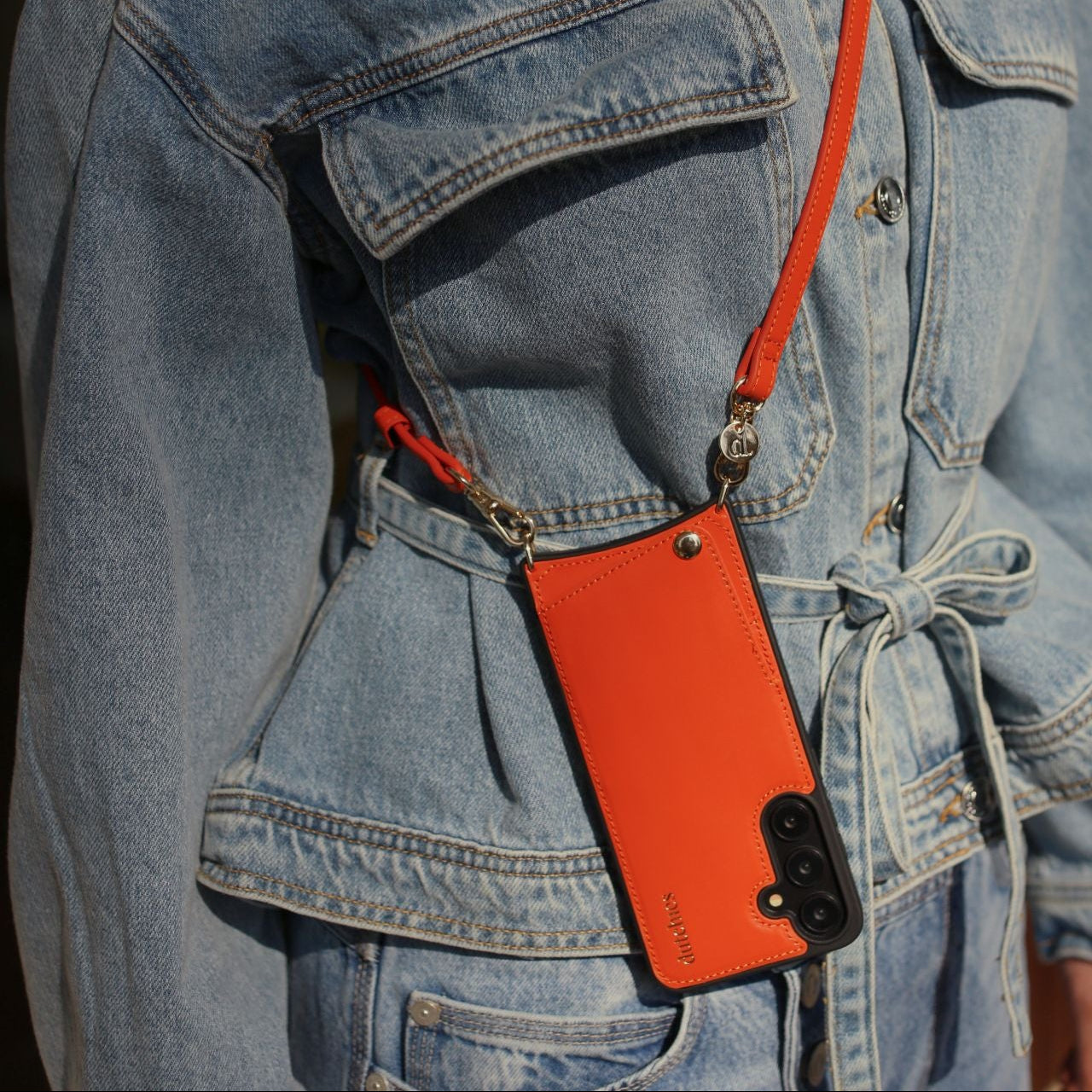 Classic set | Samsung | Orange - stylish orange leather case with strap worn over a denim jacket.